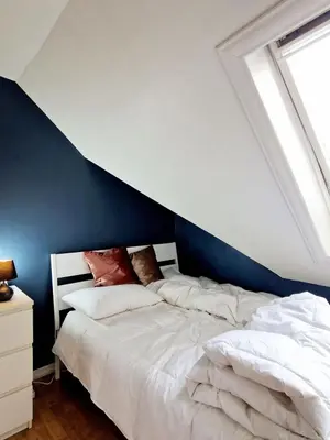 a bedroom with a bed with a blue accent wall at Top Floor Close to Grieg Hall and Town Square in Bergen