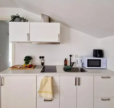 a white kitchen with a sink and a microwave at City center Terrace in quiet backyard - Stylish in Bergen