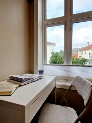 a white desk with a book and a window at Sleep well in Cozy hideout - Bryggen across the bay in Bergen