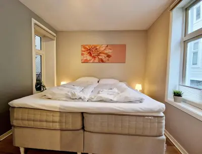 a bedroom with a bed in a room with windows at Sleep well in Cozy hideout - Bryggen across the bay in Bergen