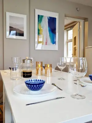 a white table with glasses and a bowl on a plate at Sleep well in Cozy hideout - Bryggen across the bay in Bergen