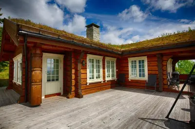 a log cabin with a large wooden deck at Spacious Cabin With Sauna & Scenic Terrace in Beitostøl