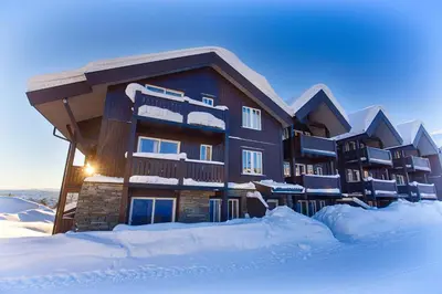 a building covered in snow with snow around it at Central Stay With Balcony, Ideal For Small Family in Beitostøl