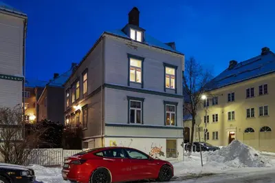 a red car parked in front of a house at Cozy downtown apartment in Trondheim