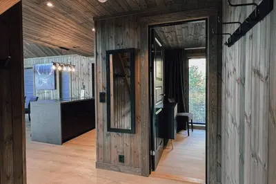 a room with wooden walls and a hallway with a mirror at Modern Mountain Cabin - Outdoor Hot Tub - 8 Beds in Torpo