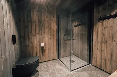 a bathroom with a toilet and a glass shower at Modern Mountain Cabin - Outdoor Hot Tub - 8 Beds in Torpo