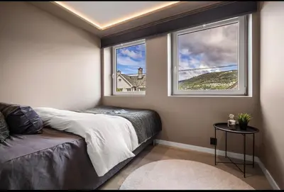 a bedroom with a bed and two windows at Central 2 story modern apartment in Bergen