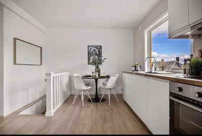 a white kitchen with a table and white chairs at Central 2 story modern apartment in Bergen
