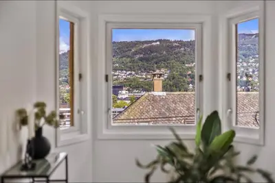 a room with three windows with a view of a city at Central 2 story modern apartment in Bergen