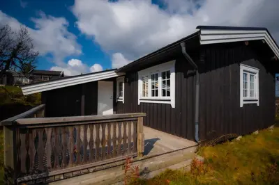 a small black house with a wooden deck at Trysilfjellet Nord 637 in Trysil