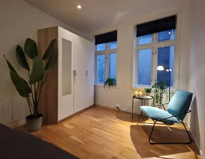a bedroom with a blue chair and a plant at City center retreat with king bed in Bergen