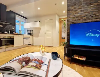a living room with a tv and a table with a book at City center retreat with king bed in Bergen