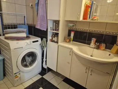 a bathroom with a washing machine and a sink at Flatåsensenteret in Kystad