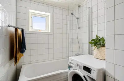 a white tiled bathroom with a washing machine at Cozy and spacious apartment in Trondheim
