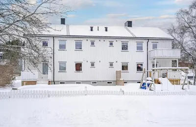 a white house in the snow with a playground at Cozy and spacious apartment in Trondheim