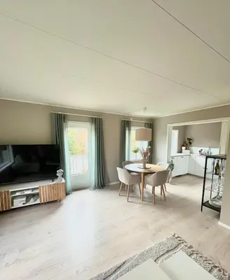 a living room with a table and a tv at Cozy and spacious apartment in Trondheim