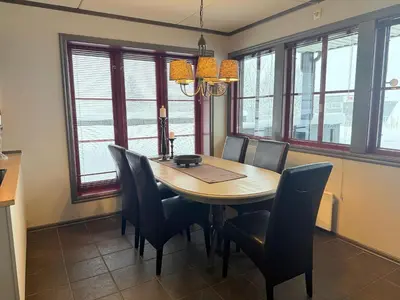 a dining room with a table and chairs and windows at Spacious Retreat With Sauna And Parking in Beitostøl