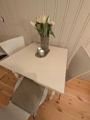 a white table with a vase of flowers on it at Koselig kjellerleilighet, gratis parkering! in Trondheim