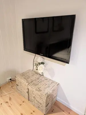 a flat screen tv hanging on a wall with a box at Koselig kjellerleilighet, gratis parkering! in Trondheim