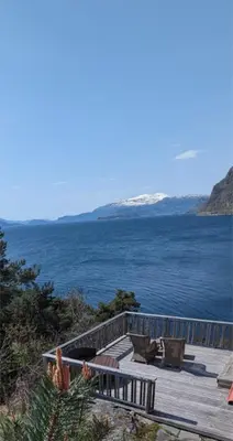 a wooden deck with benches and a view of the ocean at Hardangerfjord panorama 1 in Kvam
