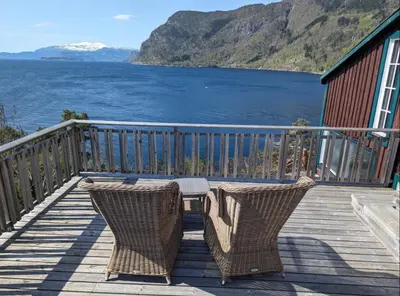 a table and chairs on a deck with a view of the water at Hardangerfjord panorama 1 in Kvam