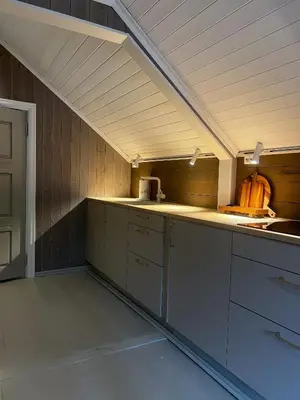an attic kitchen with white cabinets and a counter top at Grandma`s house in Flåm