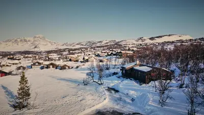 a village covered in snow with mountains in the background at Newly renovated, centrally located family cabin with mountain view in Beitostøl