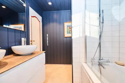 a bathroom with blue walls and a sink and a tub at Newly renovated, centrally located family cabin with mountain view in Beitostøl