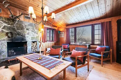 a living room with a table and chairs and a stone fireplace at Newly renovated, centrally located family cabin with mountain view in Beitostøl