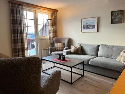 a living room with a couch and chairs and a table at Leilighet midt i sentrum in Beitostøl