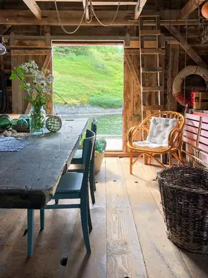 a dining room with a table and chairs and a window at Historic Villa By The Sea In Solund in Hardbakke