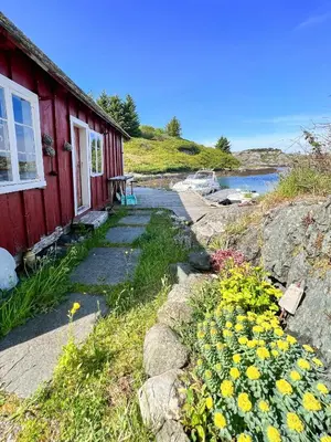 a red house with yellow flowers outside of it at Historic Villa By The Sea In Solund in Hardbakke