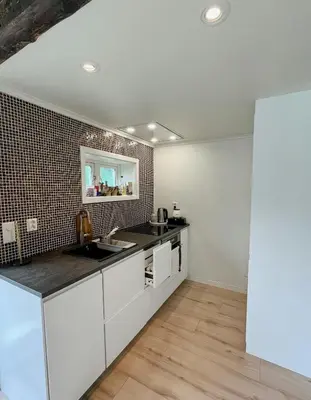 a kitchen with white cabinets and a tile wall at Unique Modern Harbour Home In Valsøyfjord in Valsøyfjord