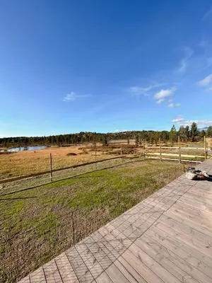 a wooden walkway next to a field with a fence at Cozy Modern Mountain Cabin At Kvamsfjellet in Kvam