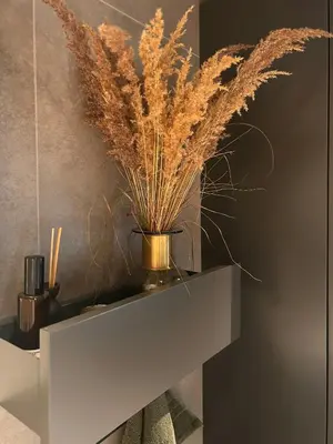 a white shelf with a vase with grass on it at Ski-In Ski-Out Apartment In Trysil in Trysil