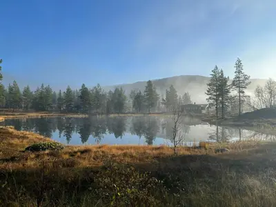 a lake with trees and a house in the background at Designer Cabin With Panoramic Views In Hovden in Bykle