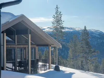 a house in the snow with mountains in the background at Modern Cabin With Panoramic View On Bringsfjellet in Lalm