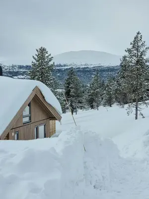 a house covered in snow next to a pile of snow at Modern Cabin With Panoramic View On Bringsfjellet in Lalm