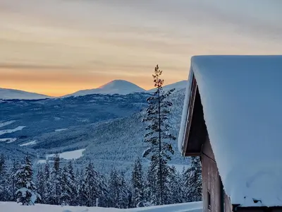 a house covered in snow with a mountain in the background at Modern Cabin With Panoramic View On Bringsfjellet in Lalm