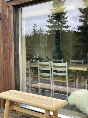 a bench in front of a window with a table and chairs at Fantastic Forest Cabin With Panoramic View in Jaren