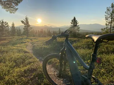 a bike parked in a field with the sunset in the background at Unique Hobbit Cabin By Hallingskarvet in Hovet
