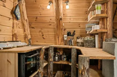 a kitchen in a log cabin with wooden walls at Unique Hobbit Cabin By Hallingskarvet in Hovet