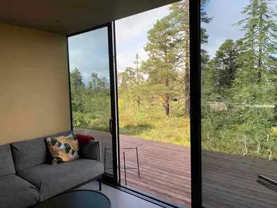 a living room with a couch and a large glass window at Modern Cabin By Snøhetta At Blefjell in Svene