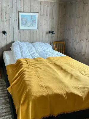 a bed with a yellow blanket on top of it at Nature-Close Cabin By The Water in Eggedal
