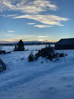 a snow covered field with trees and a building at Charming Cabin With Fantastic View In Sjusjøen in Sjusjøen