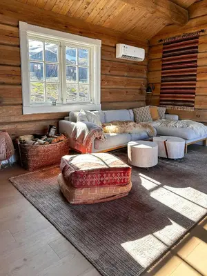 a living room with a couch and tables and windows at Spectacular Cabin With View In Jotunheimen in Eidsbugarden