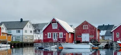 a group of colorful houses and a boat in the water at Charming Cabin On Veiholmen's Inner Harbor in Smøla