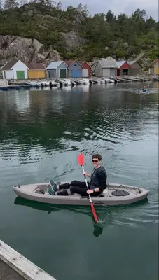 a man is sitting on a kayak in the water at Cozy Family Cabin Surrounded By Idyllic Islands in Fitjar