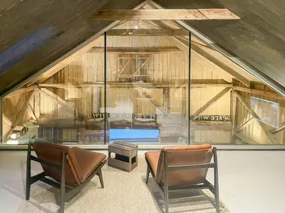 a attic room with two chairs and a window at Seaside Boathouse In Veiholmen in Smøla