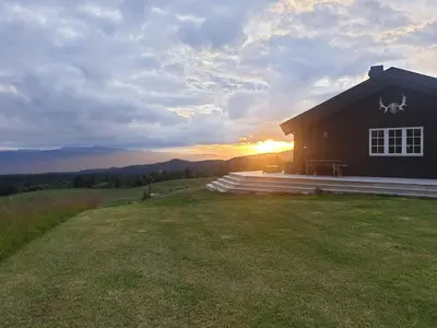 a house on a hill with the sunset in the background at Mountain Cabin With A View Over Jotunheimen in Tretten